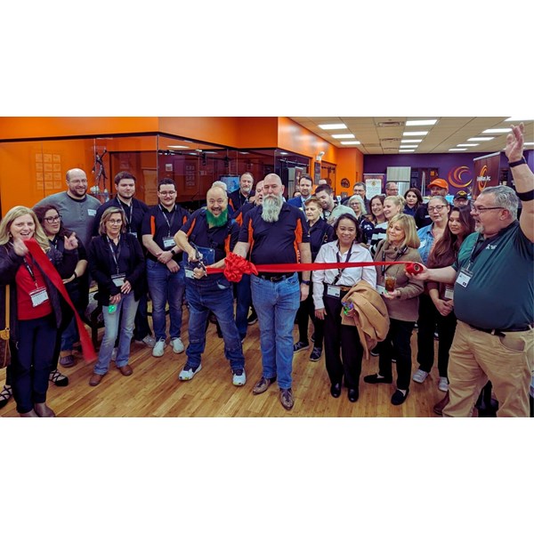 Group of people celebrating a ribbon-cutting ceremony indoors.