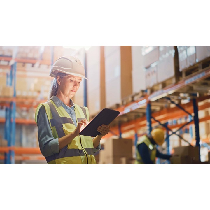 Woman in hard hat holding a tablet in a warehouse