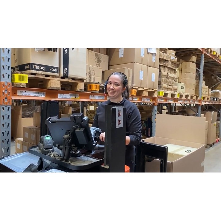 An F&H employee utilizes a headset to integrate LOGIA WMS with pick-by-voice for efficient warehouse picking.