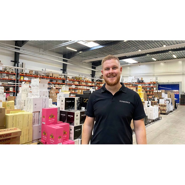 The logistics manager at Supervin poses in front of a wide range of different wines. 